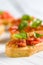 Detail of bruschetta: traditional italian appetizer with tomatoes, basil leaves and olive oil