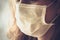 Detail of Caucasian woman wearing a white medical face mask. Sad tired look. Focus on the front part of the face, blurred