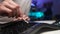 Detail close-up of unrecognizable man cleaning dirty disassembled black keyboard using cotton bud sitting at table