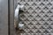 Detail of a closed door with a handle and a black metal carved background. Old metal handle on the front door