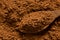 Detail of cocoa powder on a wooden spoon sitting on cocoa powder from above