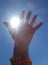 Detail color photography of womans hand catching sun rays and blue sky