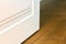 Detail of contemporary white room door on wooden yellow floor