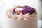 Detail of cream cake with macarons, blueberries, raspberries, purple flower and pearls