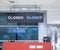 Detail of empty departure check-in counter. Sign Closed on screen. Closed airport gate.