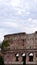 Detail of the facade with arches of the Colosseum Amphitheatrum Flavium with trees in front