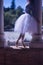 Detail of feet in classical ballet slippers of a woman in a white tutu illuminated by a ray of sunlight between two columns
