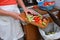 Detail of a female hand disposing of organic waste in a proper bin with kitchen in the background