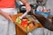 Detail of a female hand disposing of organic waste in a proper bin with kitchen in the background