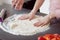 Detail of female hands making pizza from dough.