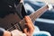 Detail of the fingers of a guitarist playing a chord on an electric guitar