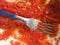 detail of a fork inside tomato sauce