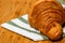 Detail of fresh croissant on wooden table. Food and breakfast concept. Close up photo of French buttery croissant