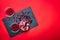 Detail of the fresh pomegranate seeds and juicy pomegranate fruit on the dark slate plate on the red background.