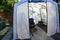 Detail of freshly build modern plastic greenhouse in garden with plastic boxes, part of steel barell as flower pot.