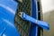 Detail of the front bumper of a blue sports car on which a blue tow strap is attached.