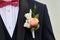 Detail of a groom& x27;s dark blue costume with a buttonhole of roses