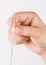 Detail of hand holding needle with thread on white background