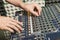 Detail of the hands of a man manipulating a mixing desk