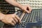 Detail of the hands of a man manipulating a mixing desk