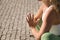 Detail of hands of middle-aged blonde woman in green leggings and white top, doing meditation and yoga exercises outdoors. Concept
