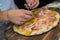 Detail of the hands of a pizza chef chef who works for the various stages of preparing a real Italian pizza homemade with yeast fl