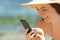 Detail of happy tourist using phone on the beach