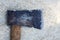 Detail of a hatchet lying in a pile of light coloured sawdust