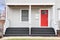 Detail of a home\\\'s front porch and red front door.