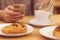 Detail image of unrecognisable man drinking coffee and holding smart phone while having breakfast in restaurant.