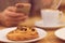 Detail image of unrecognisable man drinking coffee and holding smart phone while having breakfast in restaurant.