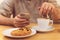 Detail image of unrecognisable man drinking coffee and holding smart phone while having breakfast in restaurant.