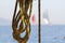 Detail image of wooden pulley with ropes of an classical sailing yacht. ocean and sailing boats in the blurry background