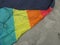 Detail of a kite in rainbowcolors with black threads laying on the beach of Velsen Netherlands