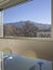 Detail of a large window overlooking nature and a glass table with two chairs in front