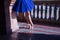 Detail of legs and feet of adult female classical ballet dancer in blue tutu doing figures on the terrace of a square next to a