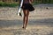 Detail of the legs of a young surfer girl walking on the beach