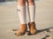 Detail of little girl boots on the beach