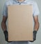 Detail of man with black gloves holding a cardboard box for delivering products on gray background.