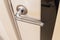 Detail of a metal handle on a white door horizontal.