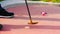 Detail of a miniature golf putter shortly after teeing off with a pink miniature golf ball in the background