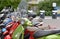 Detail of mopeds of various colors parked in row.