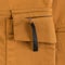 Detail of ocher colored cargo pants. Zipped side pocket with black tab