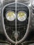 Detail of old french car with radiator grille and round light, vintage and retro background