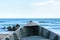 Detail of old wooden boat on beach sand with blurry blue water sea in the background