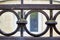 Detail of an old wrought iron fence with a round pattern covered with moss