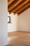 Detail of an open door, empty white room with exposed wood beams and hardwood floors