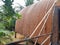 Detail of oval raftan structure in a wooden cabin among exuberant tropical vegetation. Coconut leaf house roof over murky waters