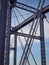 Detail of painted riveted bridge against blue sky.