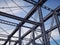 Detail of painted riveted bridge against blue sky.